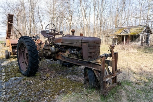 Fototapeta an old tractor parked in front of a shack in the woods