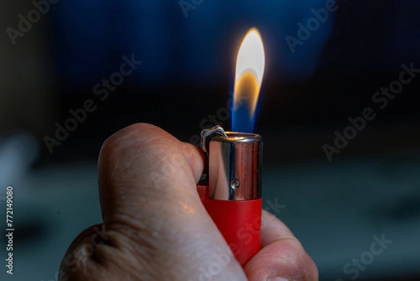 Fototapeta Mano sujetando mechero rojo encendido