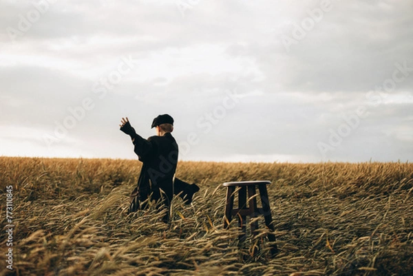 Obraz a village boy in a cap and jacket, 9 years old, runs in a wheat field.