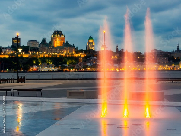 Obraz Vu du centre de la ville de Québec illuminée de l'autre côté du Saint-Laurent la nuit l'été avec une fontaine lumineuse orange