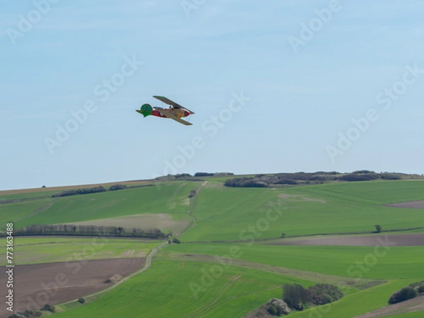 Obraz Avion de guerre allemand jaune rouge et vert en vol au-dessus des champs