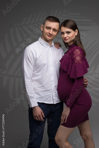 Obraz couple posing in a studio, portrait of a couple, pregnant couple standing, pregnant woman on a grey background, 9 month