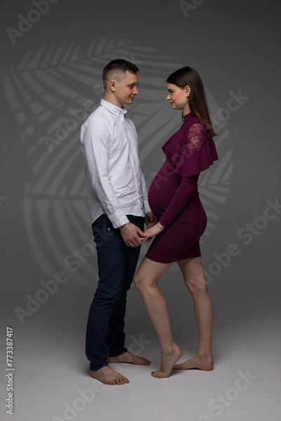 Obraz two people, portrait of a pregnant couple on a grey background, pregnant couple standing