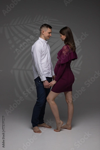 Obraz couple in a studio, portrait of a couple, pregnant couple standing, pregnant woman on a grey background, 9 month