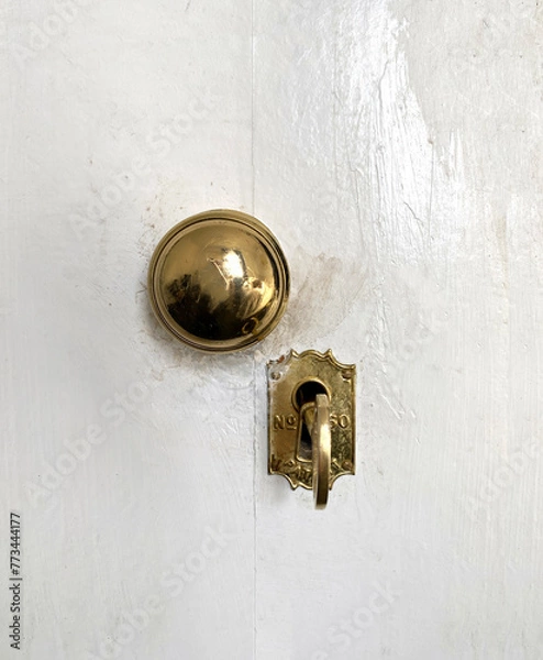 Fototapeta Antique door lock. Golden door handle with antique gold-engraved crest. Ancient lock with key. Old metal key in the keyhole.