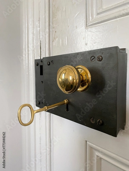 Fototapeta Ancient door lock with old metal key in the keyhole. Golden door handle.