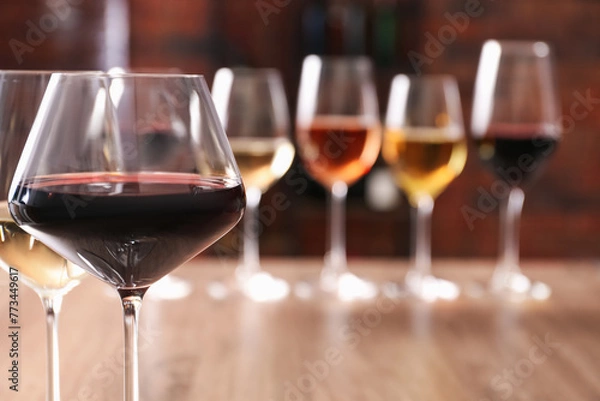 Fototapeta Tasty red and white wines in glasses against blurred background, space for text
