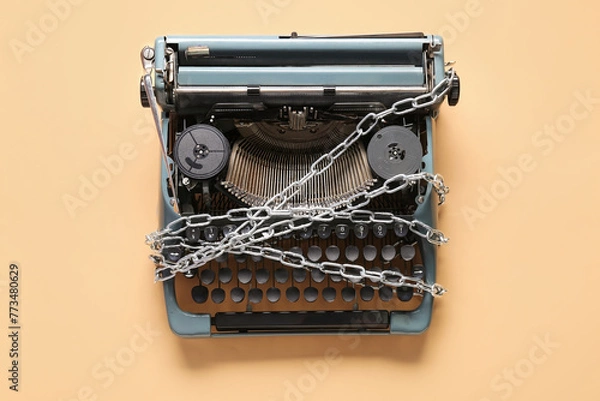 Fototapeta Vintage typewriter with chains on beige background. Printing ban concept