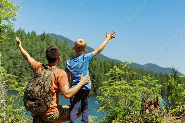 Fototapeta Happy father son hikers sitting together in mountain lake forrest setting, travel together active healthy lifestyle family vacations holiday
