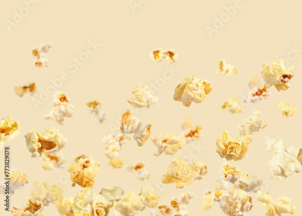 Fototapeta Tasty fresh popcorn flying on beige background