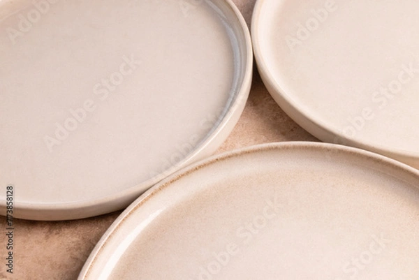 Fototapeta Beige ceramic dinner plates on a brown stone tabletop.