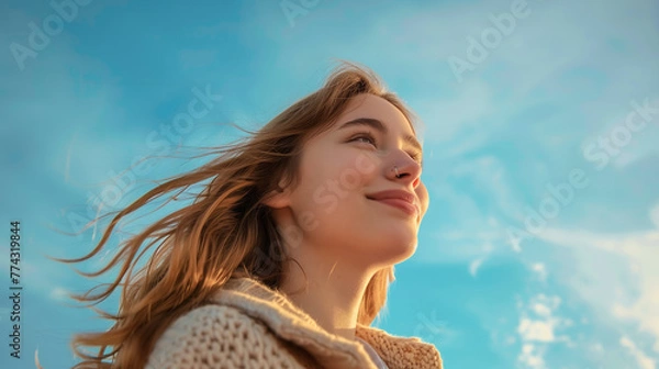 Fototapeta Ethereal lighting similar to fine art portraiture, capturing the joy and confidence of a stylish 19-year-old girl against a solid sky blue background