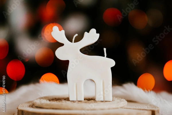 Obraz Cute deer shaped soy wax candle, Christmas lights in the background 