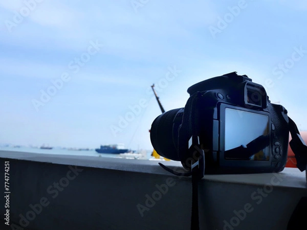 Obraz Camera dslr closed up above wall with sea and ship view	