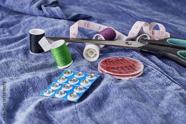 Obraz scissors needles measuring tape and thread on the background of torn jeans the concept of reasonable consumption of needlework for small businesses