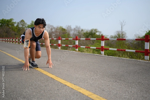 Fototapeta Full body length shot of sporty man in running start pose. Motivation and healthy lifestyle concept