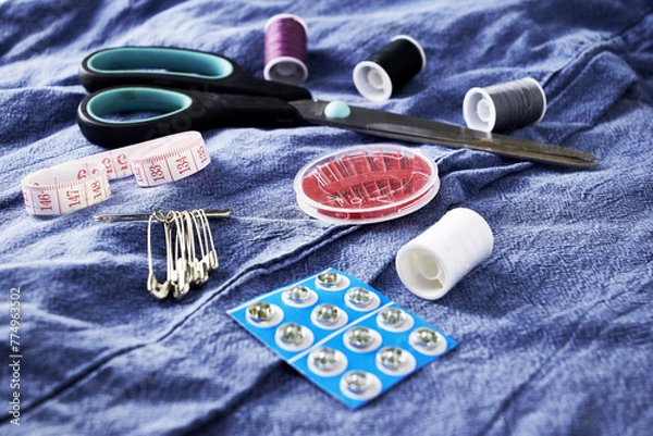Obraz scissors needles measuring tape and thread on the background of torn jeans the concept of reasonable consumption of needlework for small businesses