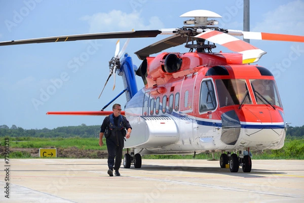 Fototapeta offshore helicopter pilot is walking and smiling beside of S92 h