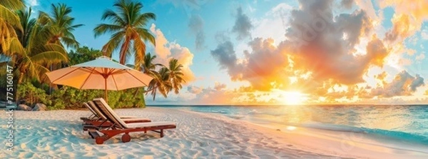Fototapeta Beach chairs and umbrella on the white sand beach with palm trees, sunset light