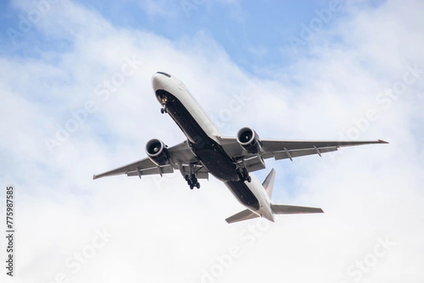 Fototapeta White passenger airplane flying in the sky amazing clouds in the background