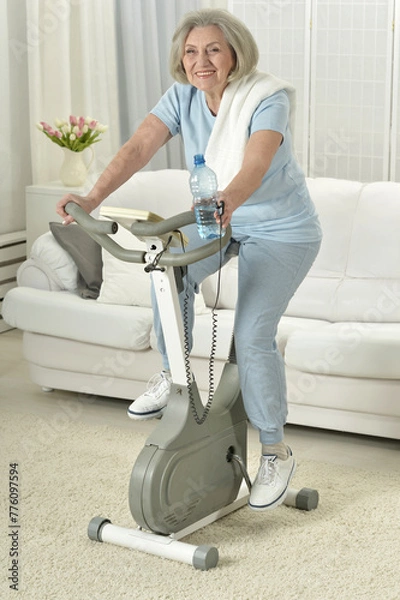 Fototapeta Elderly woman exercising on an exercise bike