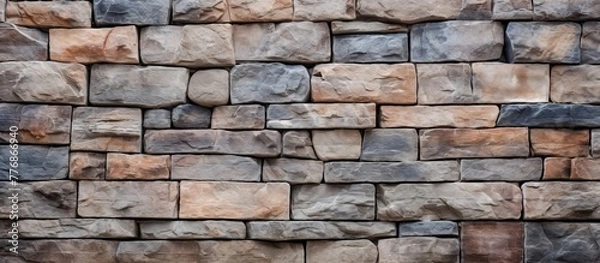 Fototapeta Close up view of a textured stone wall with a bright red fire hydrant standing in front of it