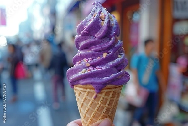 Obraz A hand holds a purple ice cream cone with a swirl in the air, blurred people are walking in the background