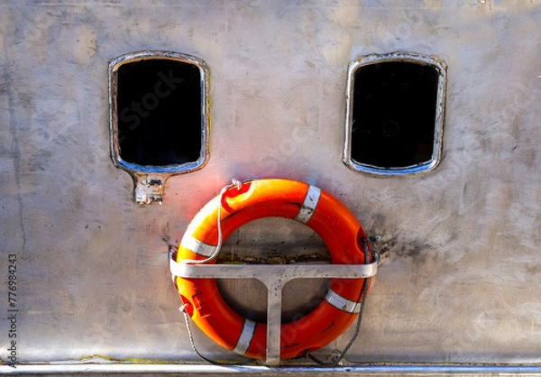 Fototapeta Windows and orange lifebuoy of boat forming a sad face