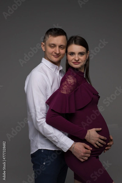 Obraz portrait of a pregnant couple on a grey background close up, fashion pregnant model posing in studio, pregnant woman stands on a grey background, studio shoot