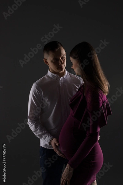 Obraz portrait of a couple, pregnant couple on a black background close up, fashion pregnant model, pregnant woman stands on a black background, studio pregnancy photo shoot