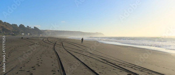 Fototapeta Person walking in the distance on Sand beach during windy summer day on pacific ocean (Iloca, Chile)
