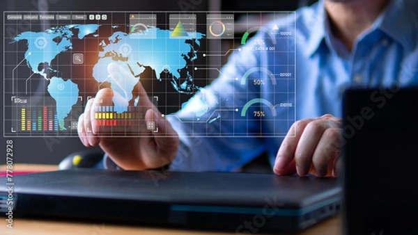 Obraz Businessman touch the global map on virtual screen checking business growing each location. Laptops on wood table in office room, business chart and graph analysis concept.