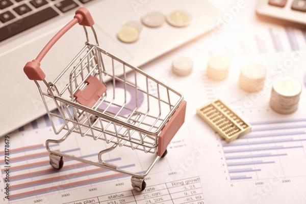 Fototapeta Coins, abacus, and carts placed on data reports