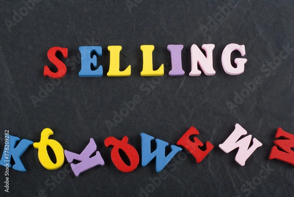 Fototapeta SELLING word on black board background composed from colorful abc alphabet block wooden letters, copy space for ad text. Learning english concept.