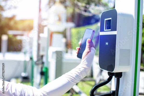 Fototapeta EV Driver use smartphone to scan QR Code on electric vehicle charging stations to pay for electricity.