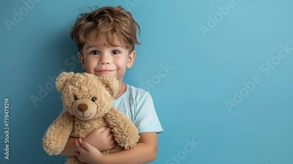 Fototapeta Little boy hugging stuffed toy on pastel blue background