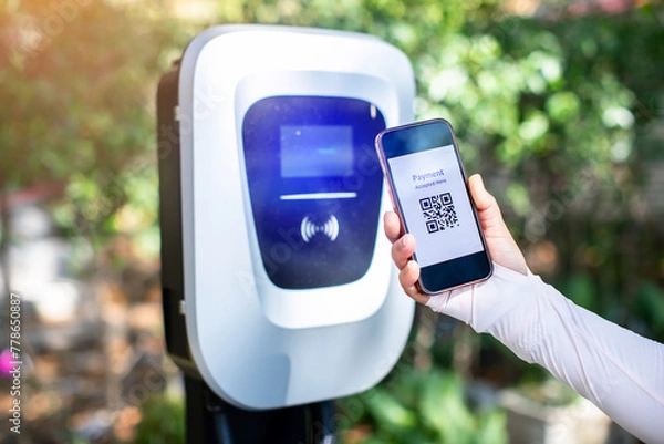 Fototapeta EV Driver use smartphone to scan QR Code on electric vehicle charging stations to pay for electricity. The concept of QR scanning payment instead of cash.