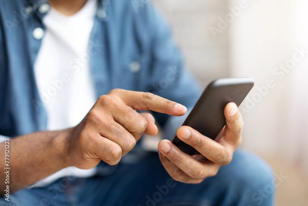 Fototapeta Black Man Using Smartphone Indoors With Focus on Hand