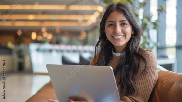 Obraz Latina freelancer, woman 25 year old Hispanic holding an open laptop, with a modern office background.