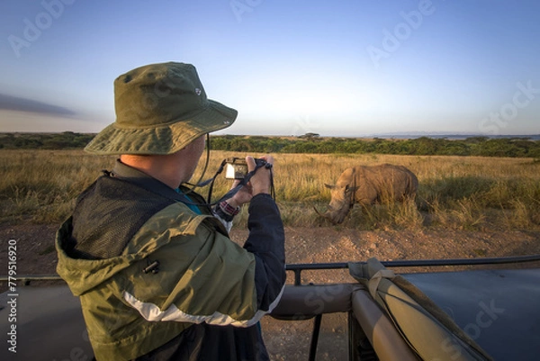 Fototapeta tourist photographs a wild leopard during a safari tour in Kenya and Tanzania. Concept Travel and adventure through wild Africa. man with a camera in an open-top safari car is traveling in Africa.