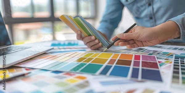 Fototapeta Two Focused Graphic Designers Choosing Color Swatches for Creative Branding with Laptop on Desk