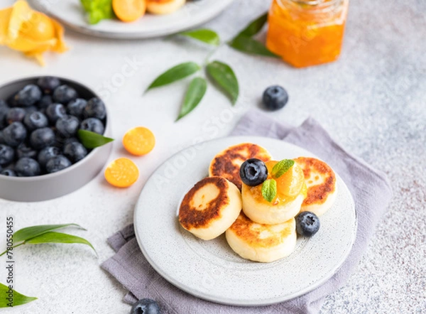 Obraz Cottage cheese pancakes, sweet curd fritters with blueberry and physalis. Syrniki with jam and berries for healthy breakfast.