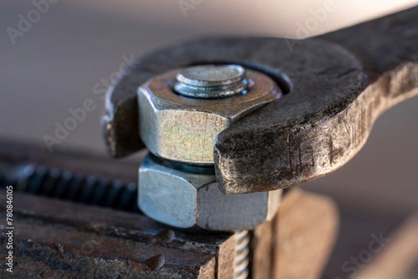 Fototapeta Loosening the nut using a wrench and a vise. Using old spanner wrench and clamp to remove nut from bolt, closeup