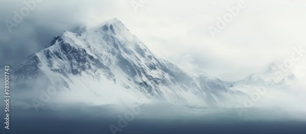Fototapeta Majestic snowy mountain peak shrouded in clouds, creating a serene and picturesque scene in nature