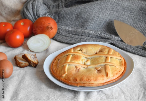 Fototapeta Freshly cooked round empanada on a background of fabrics in nude tones