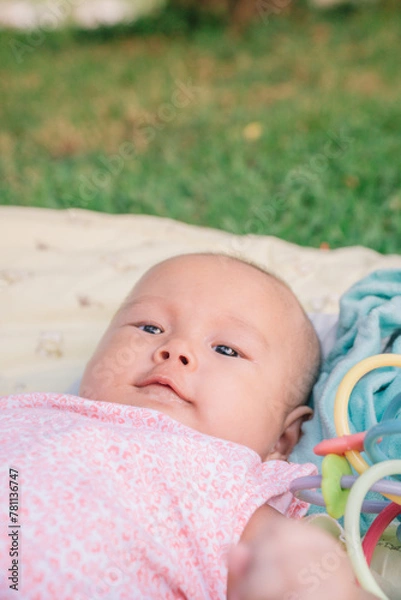 Obraz Infant Baby Girl is laying on her back in a pink bodysuit with a development toy for teething.