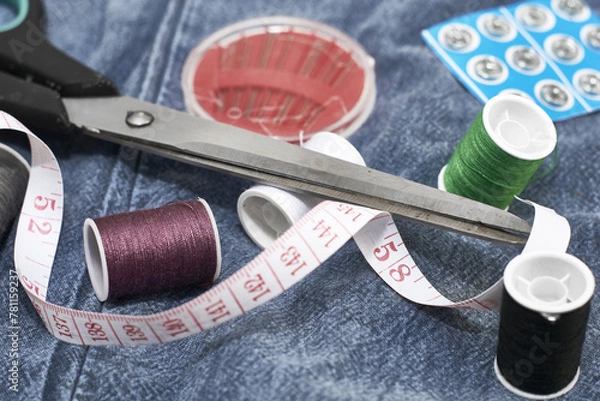 Obraz scissors needles measuring tape and thread on the background of torn jeans the concept of reasonable consumption of needlework for small businesses