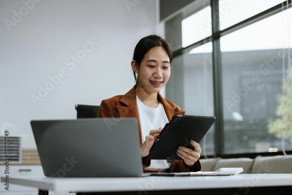 Fototapeta Business woman sitting at her desk, reading stats and graphs on paperwork at the office.