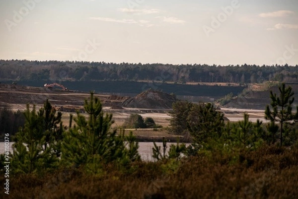 Obraz Bulldozer mining a landscape for raw materials against pine forests
