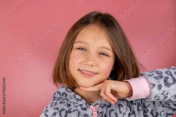 Obraz Portrait of a beautiful smiling brunette girl 8 years old on a pink background in pajamas close-up